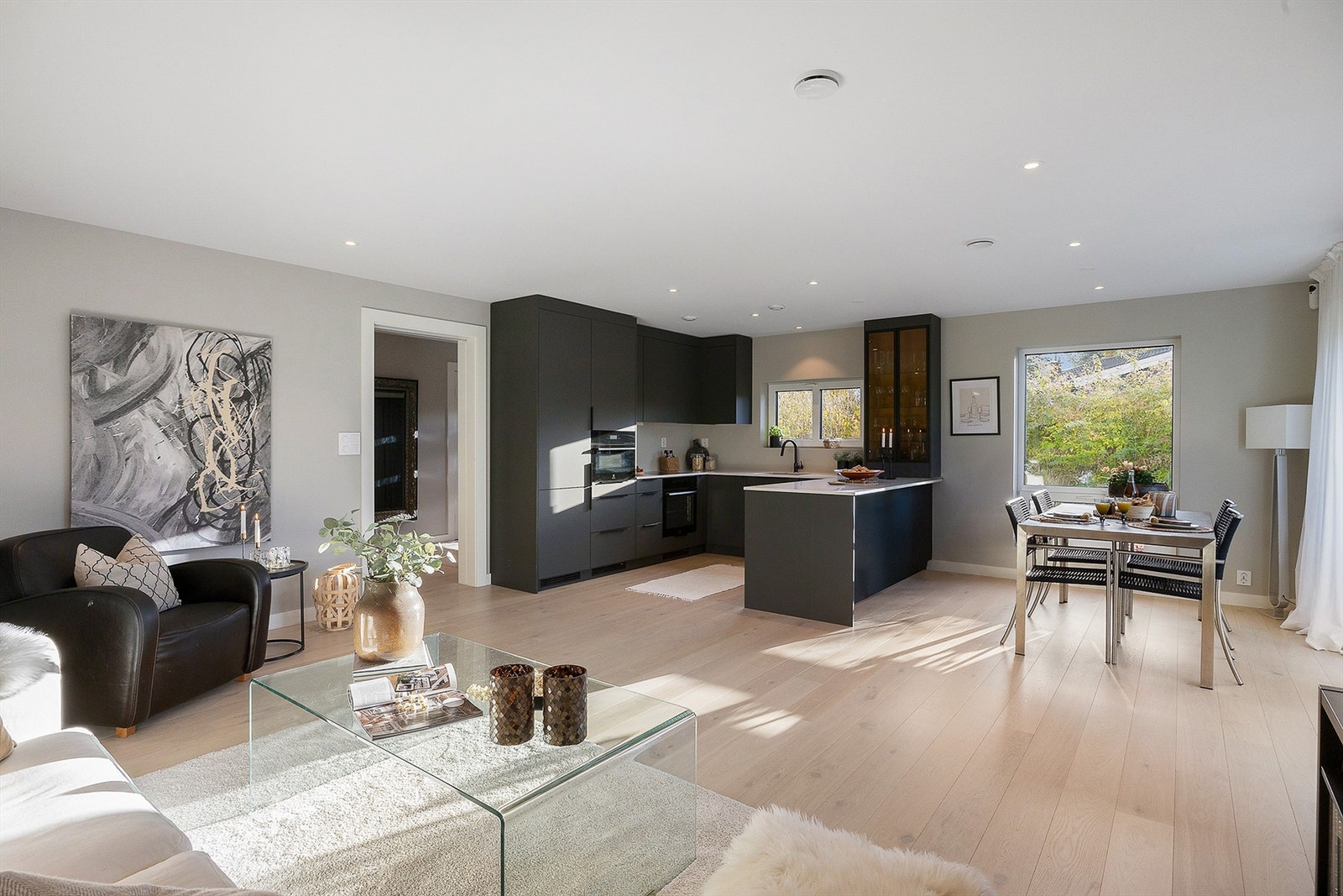 Praktisk åpen løsning mellom stue og kjøkken, med lyse vegger og lys eikeparkett som gir en lys og luftig atmosfære Galleribilde