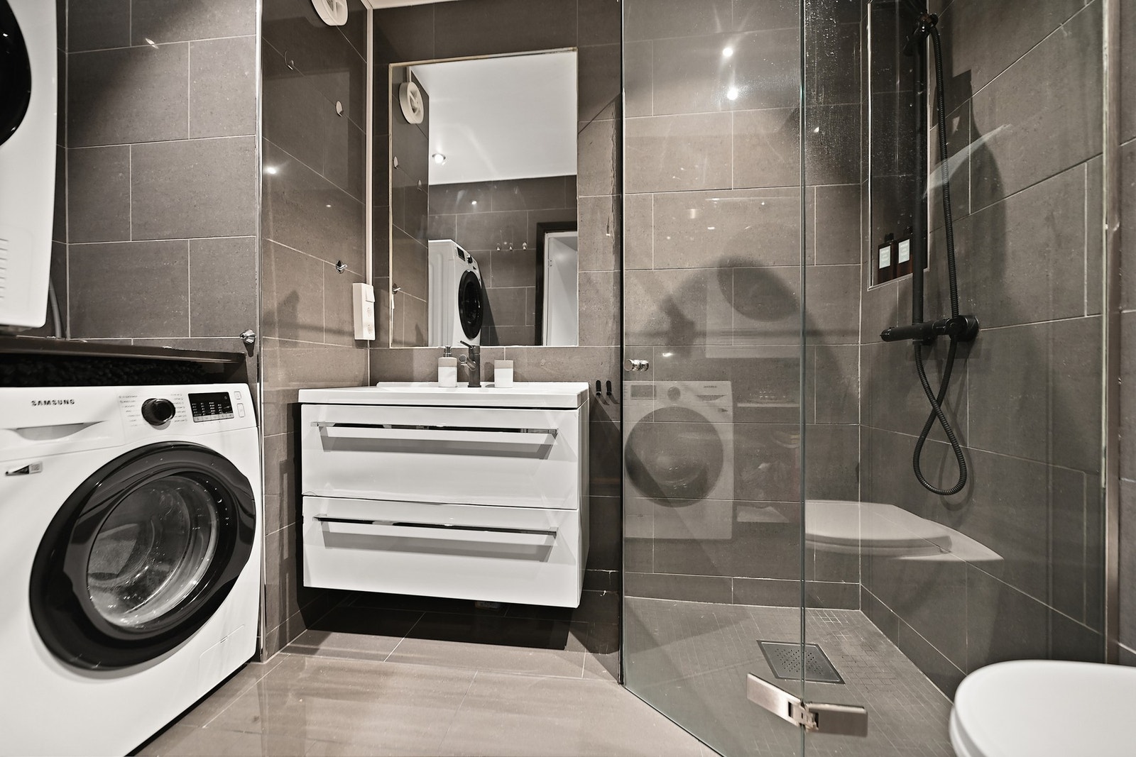 Badet er innredet med servantskap, vegghengt wc, opplegg for vaskemaskin, speil og dusjhjørne med takdusj. Nytt blandebatteri i dusjen og på servantskapet i 2024. Galleribilde