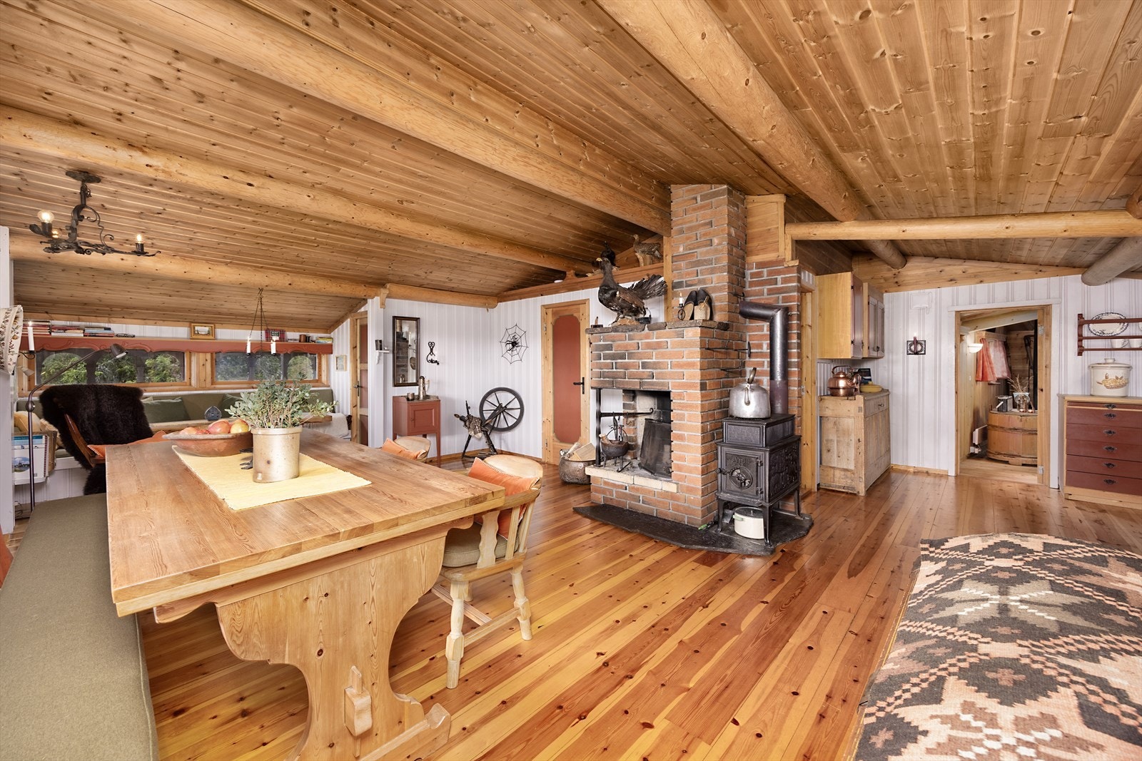 Hovedhytta har en åpen stue- og kjøkkenløsning. Høyt under taket, som har håndbarkede rundstokker fra tomta. Galleribilde