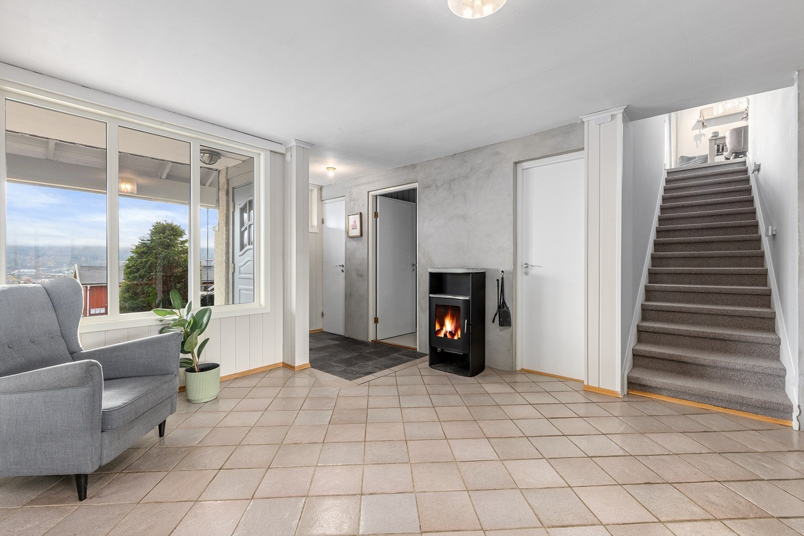 Velkommen inn! Romslig entré med flislagt gulv og peisovn. Galleribilde