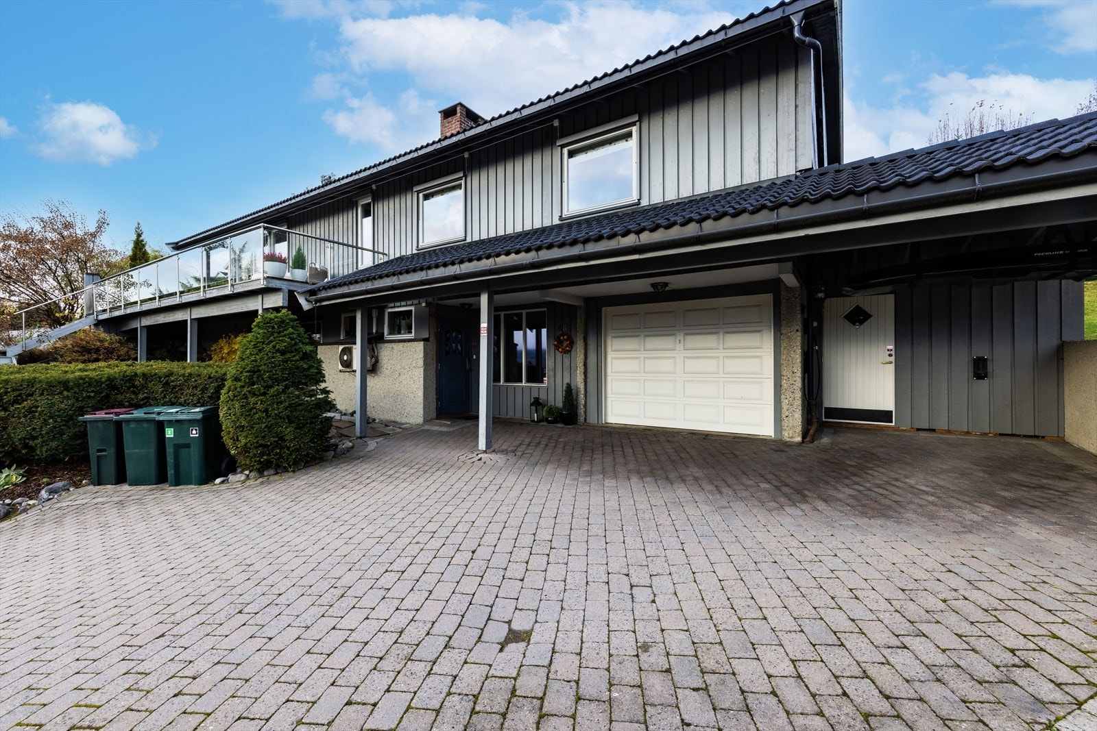 Stor brosteinsbelagt gårdsplass, samt parkering i innebygget garasje og carport. Galleribilde