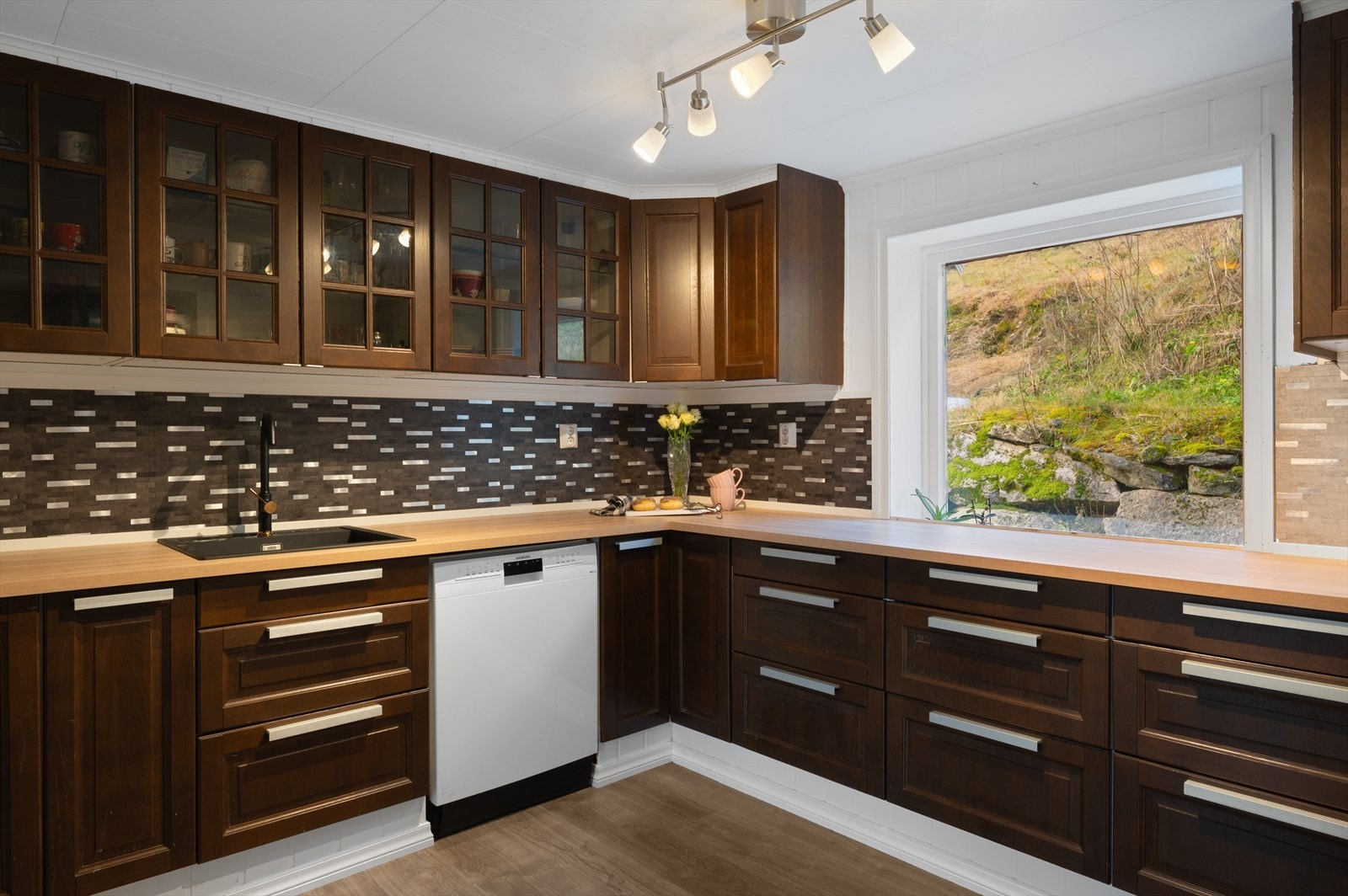 Stort kjøkken med profilerte fronter og vitrineskap, samt benkeplate i laminat. Galleribilde