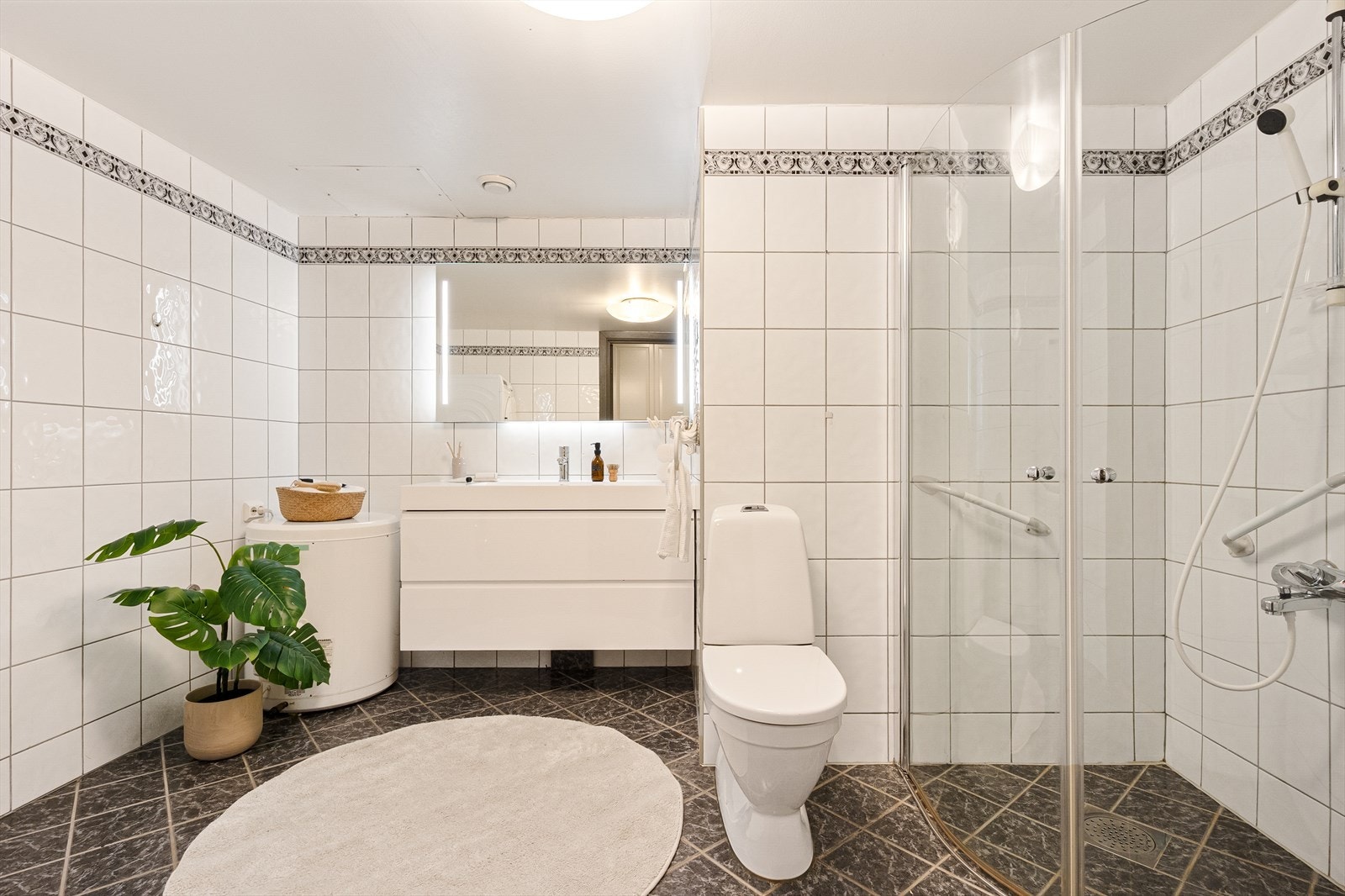 Flislagt bad med dusj hjørne, wc, vask og opplegg for vaskemaskin Galleribilde