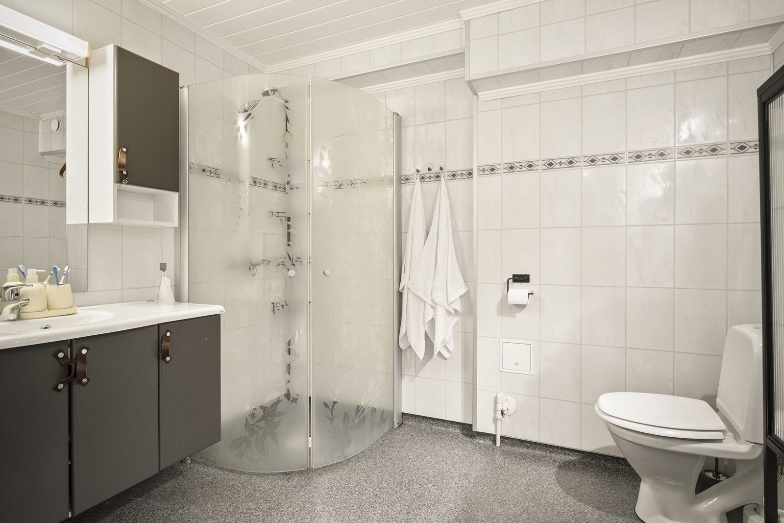 Moderne bad med dusjhjørne, servant med underskap og opplegg for vaskemaskin - alt du trenger i hverdagen. Galleribilde