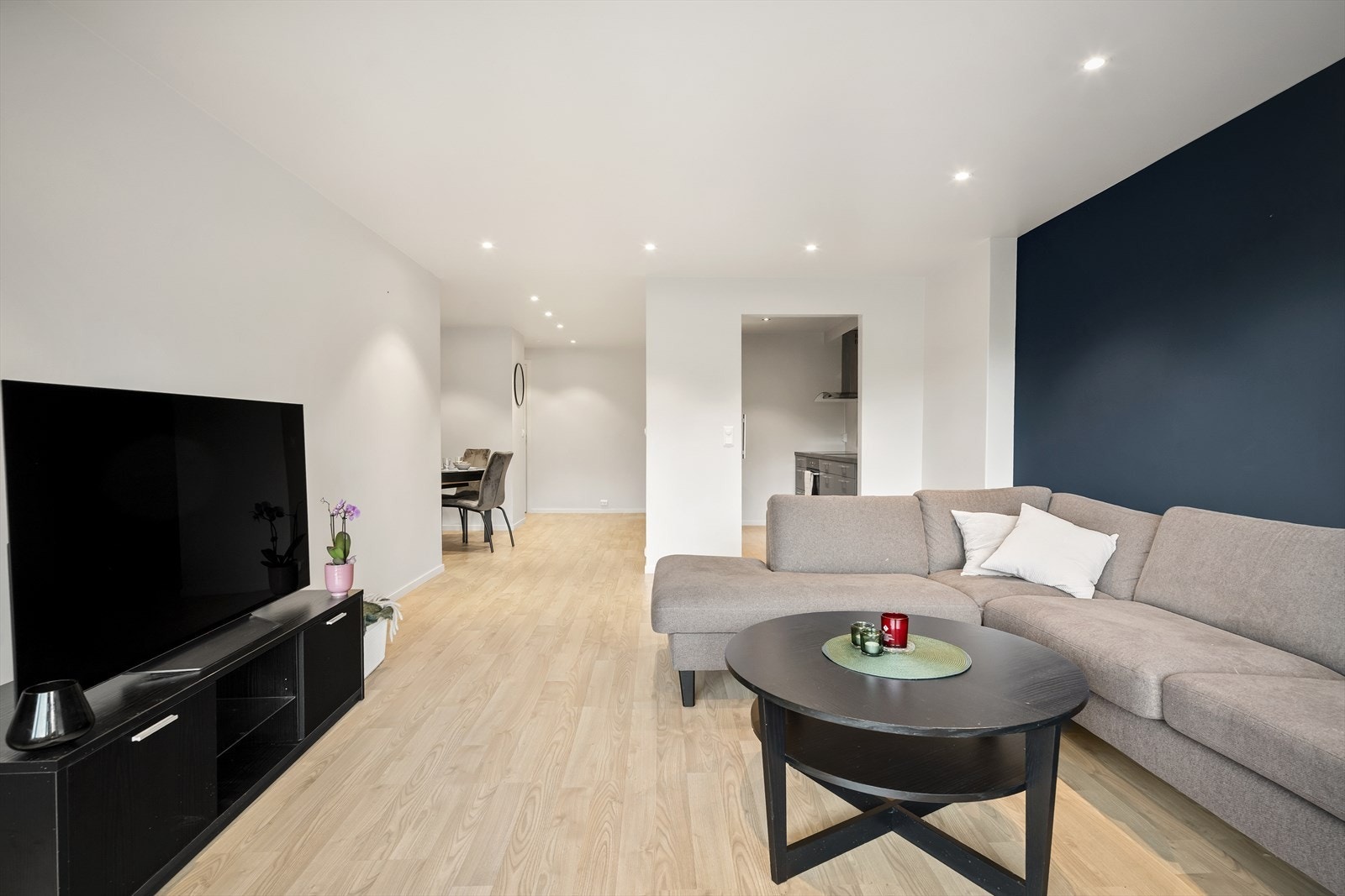 Gjennomgående laminatgulv og slette, malte vegger gir stuen et tidløst og moderne preg. I himlingen er det montert moderne downlights Galleribilde