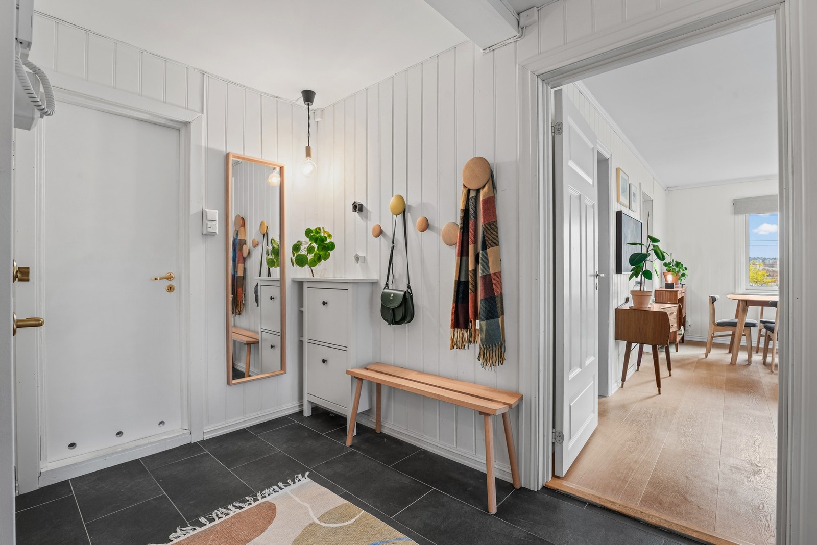 Entréen har fliser på gulv, panel på vegg og medfølgende skoskap Galleribilde