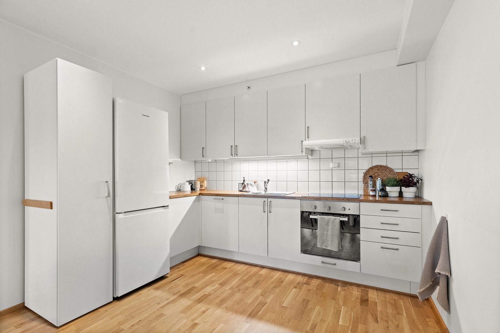 Kjøkkeninnredningen har glatte hvite fronter, benkeplater i laminat og nedfelt kum av stål. Galleribilde