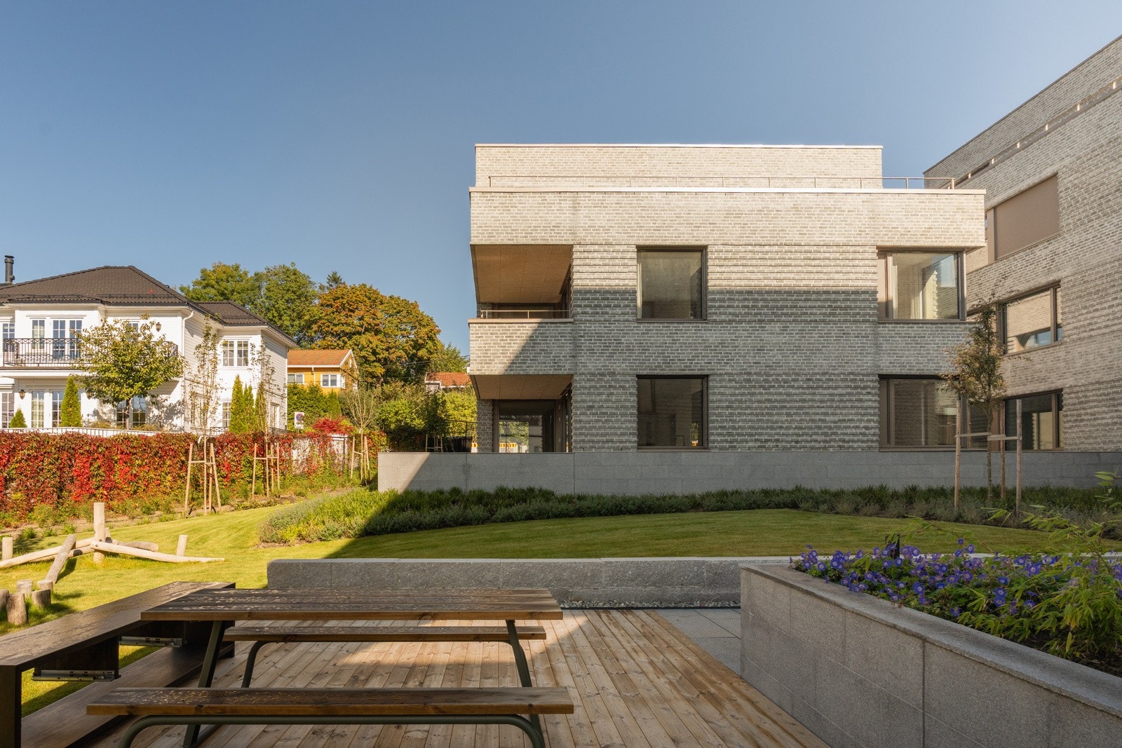 Heller, kantsten og murer i lys granitt bidrar til å strukturere tomtens grøntrealer, forbindelseslinjer og adkomster.