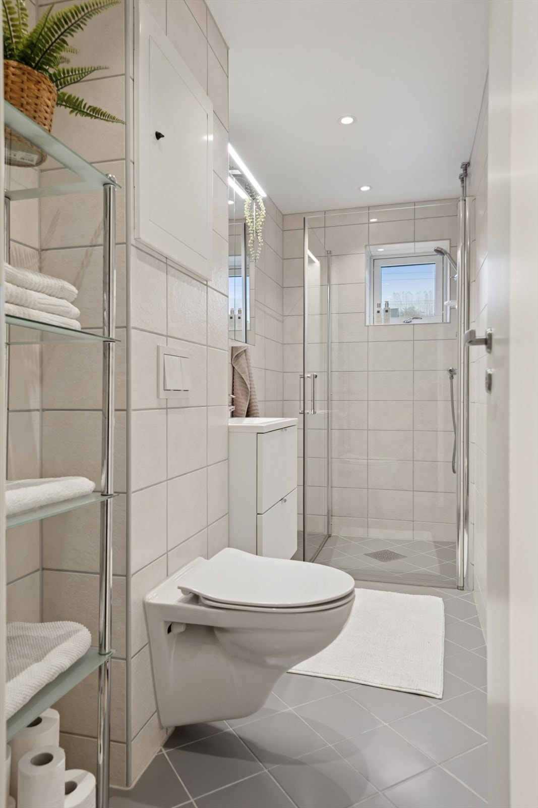 Delikat flislagt bad fra 2020. Rommet er utstyrt med dusjhjørne, vegghengt toalett og en lys og moderne baderomsinnredning. Galleribilde