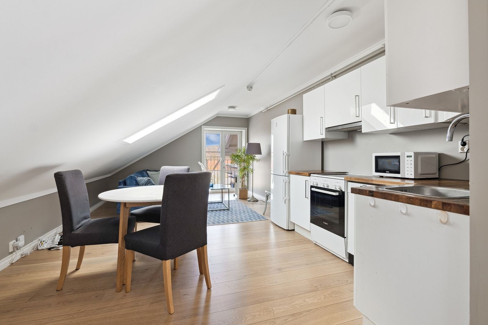 Pent kjøkken i hvite fronter med god skap og benkeplass. Galleribilde