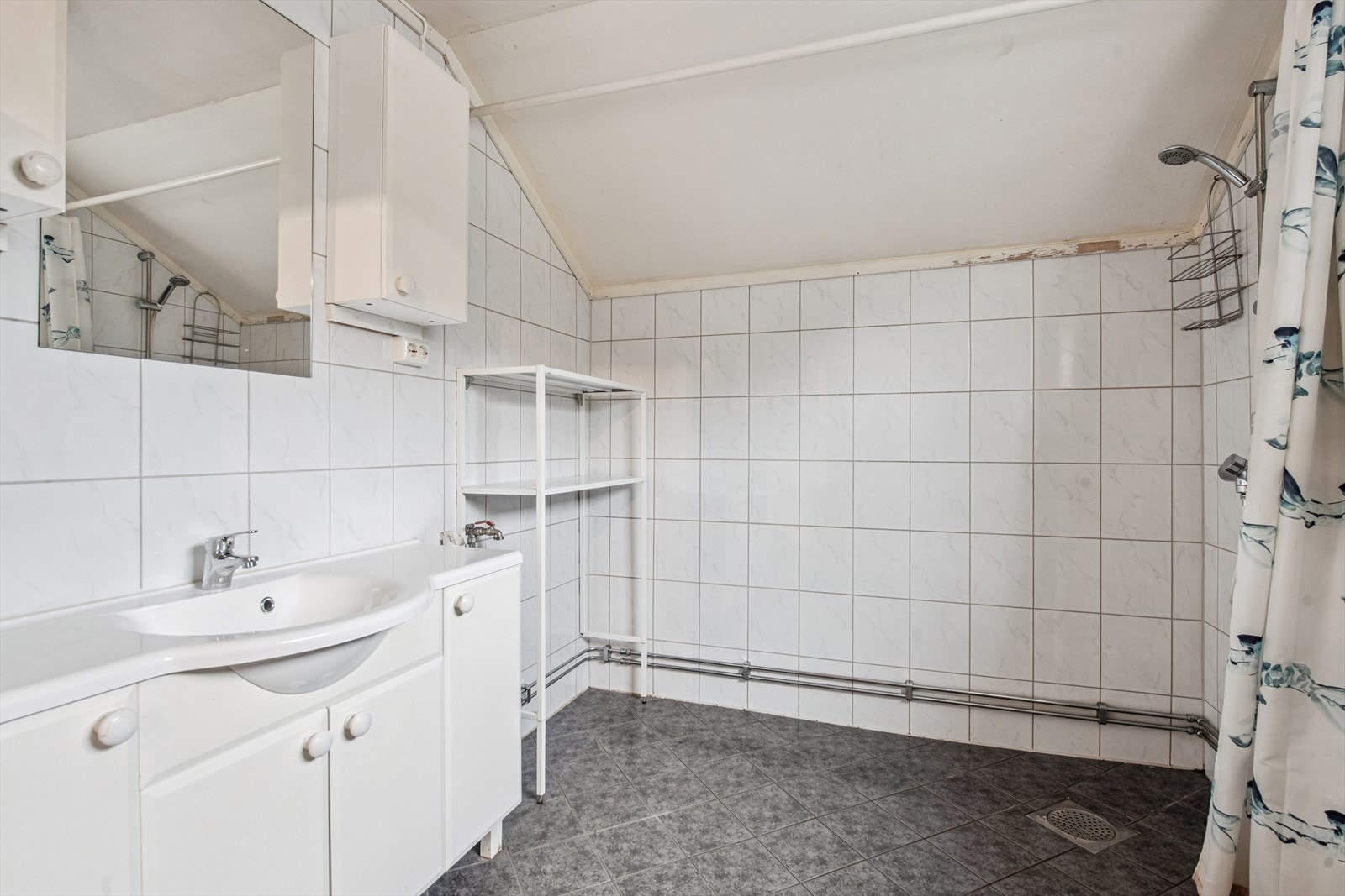 Badet inneholder toalett, åpen dusj m/forheng, opplegg for vaskemaskin og baderomsinnredning. Galleribilde