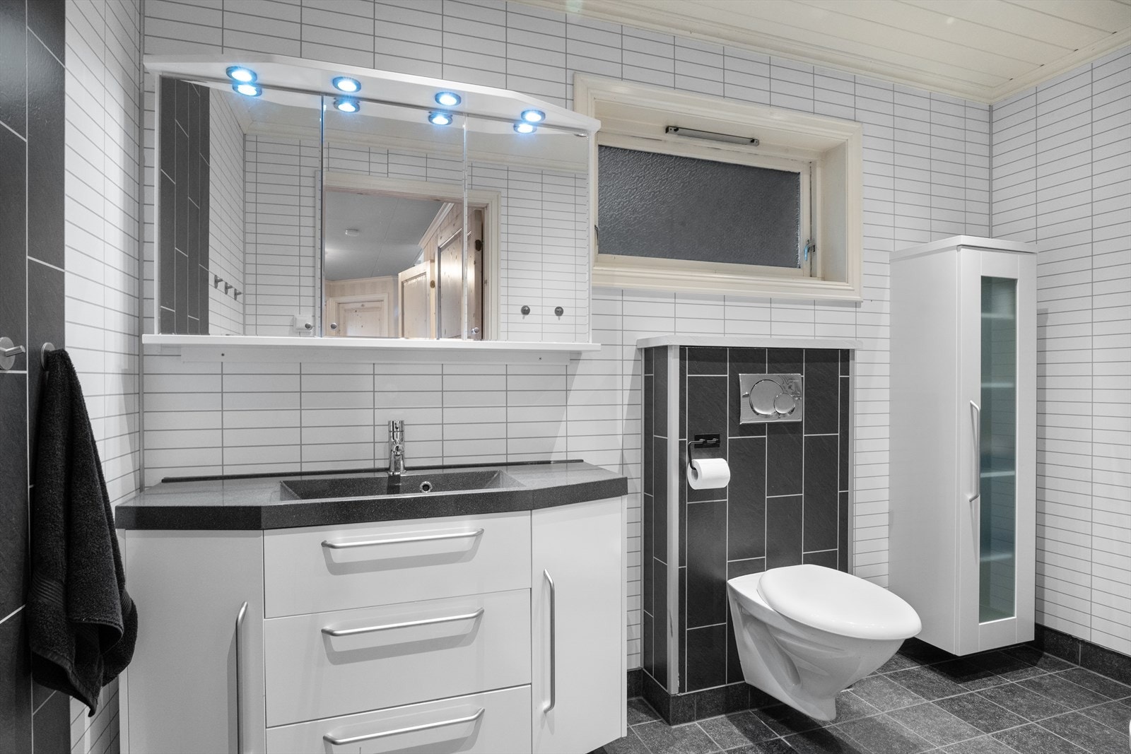 Pent og tidløst bad som inneholder baderomsinnredning, overskap m/speil, vegghengt toalett og dusjkabinett. Galleribilde