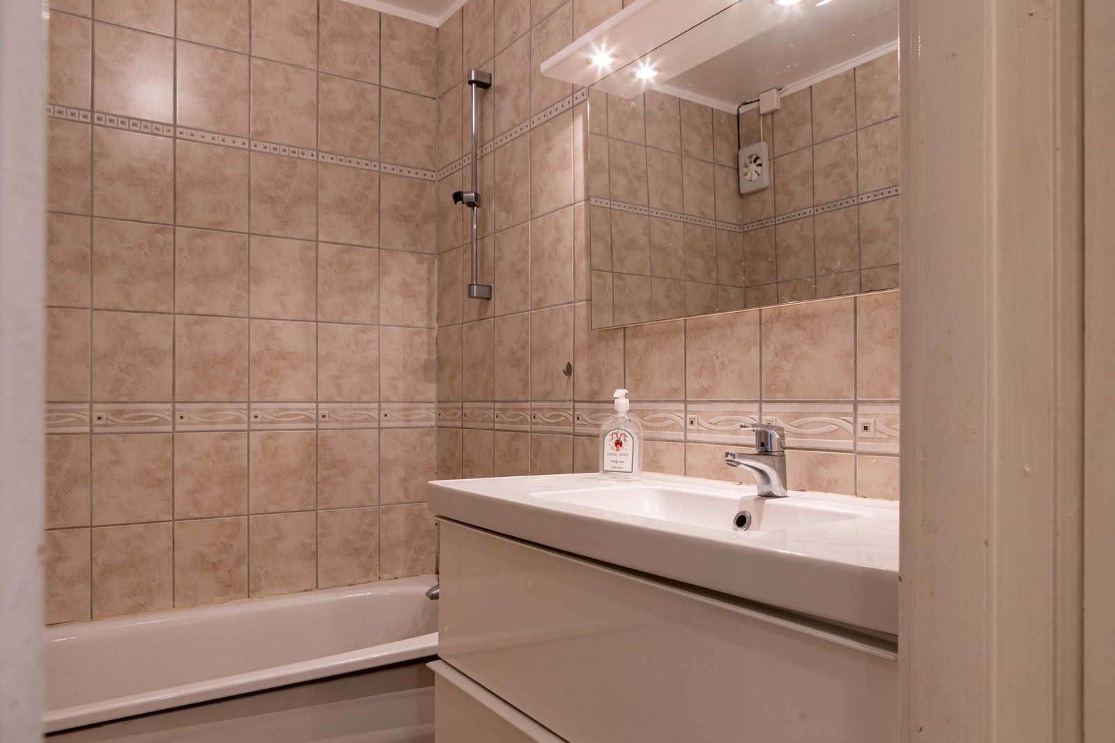 Romslig baderom. Rommet er helfliset i lyse, tidløse toner. Galleribilde