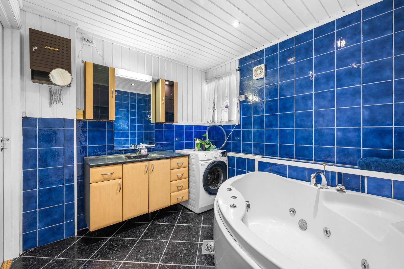 Badet inneholder badekar, servant, benkeskap og veggskap med speil- og glatte fronter. Galleribilde