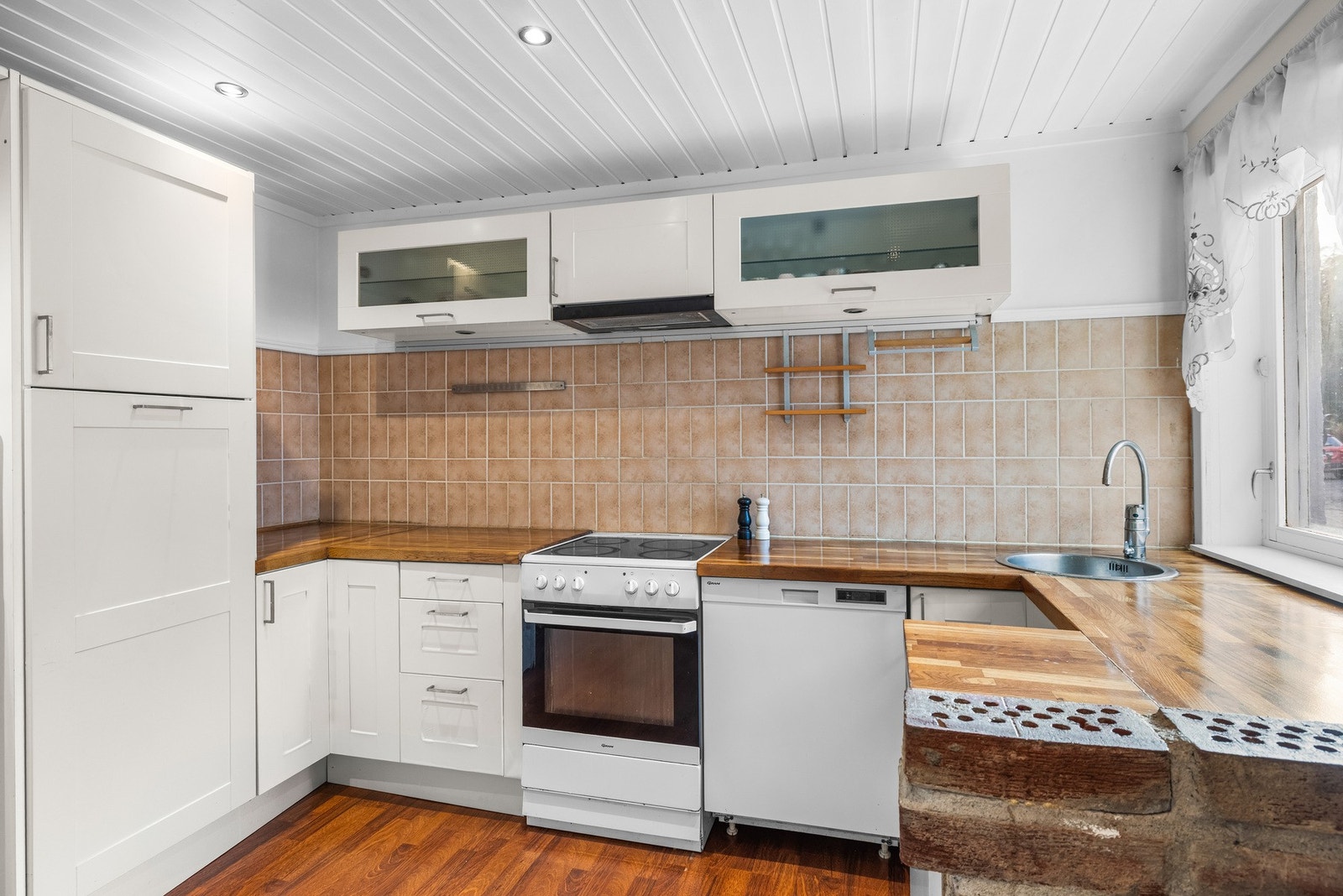 Innredningen er tidløs med profilerte fronter og heltre benkeplate. Det er fliser på vegg mellom benkeskap som gjør renhold lett. Galleribilde