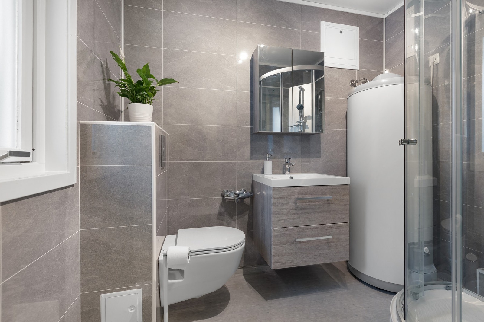 Oppusset og moderne bad med vegghengt toalett, dusjkabinett og baderomsinnredning. Badet ligger i tilknytning til entre. Galleribilde