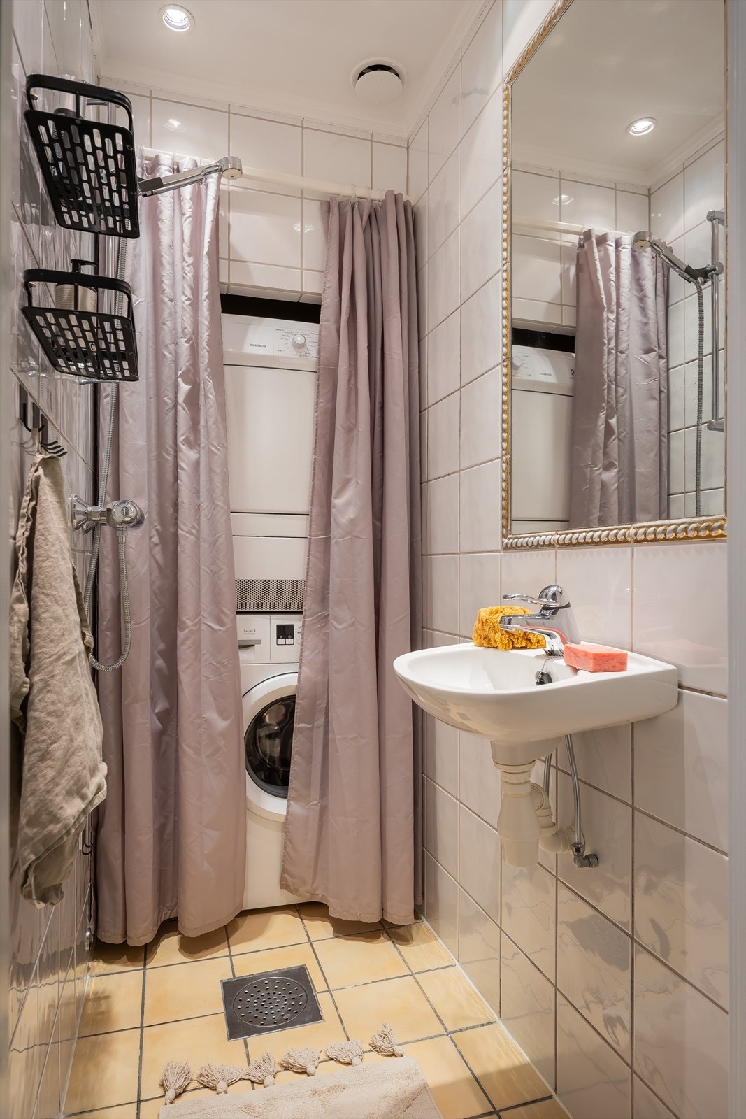 Flislagt bad med plass til både vaskemaskin og tørketrommel som kan skjules bak dusjforheng. Galleribilde