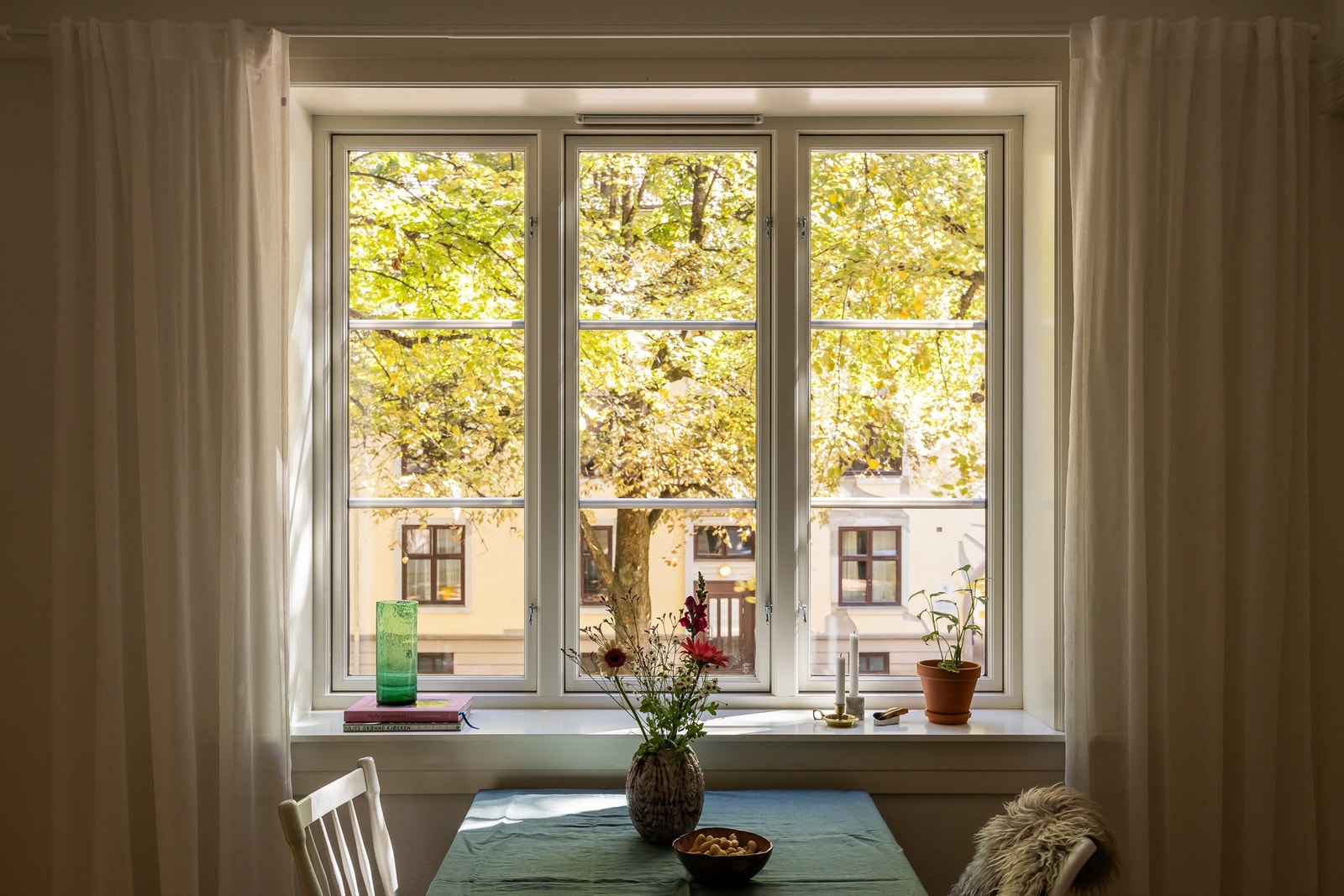 Det store vinduet i stuen fyller leiligheten med naturlig lys. Leiligheten ser utover en flott allé med grøntområder rett utenfor vinduet. Galleribilde