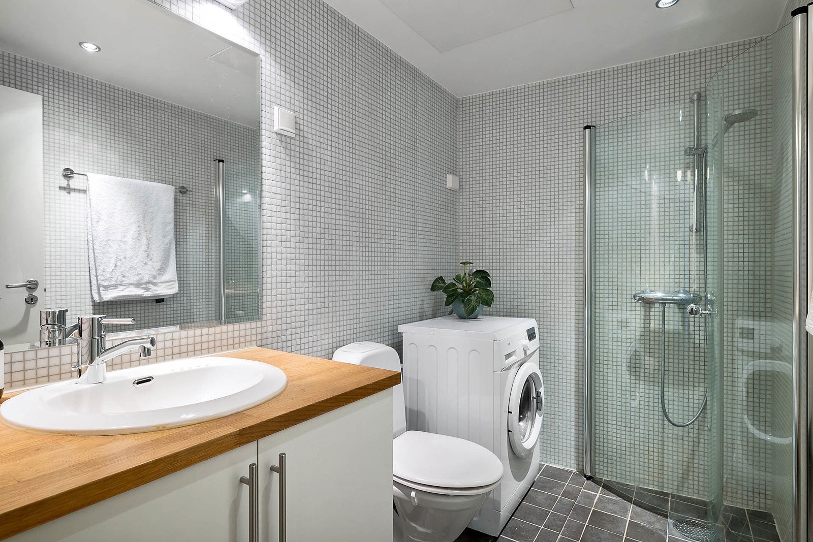 Romslig flislagt bad med varmekabler og downlights. Opplegg for vaskemaksin Galleribilde