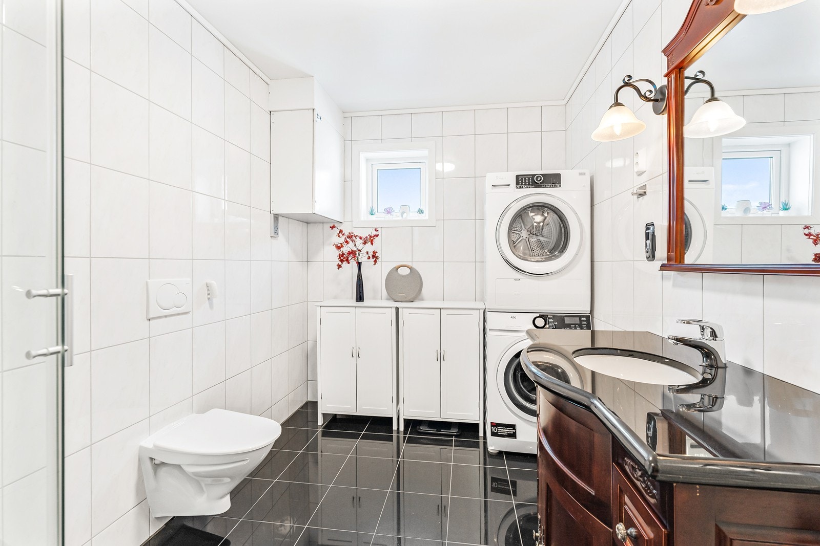 Badet er innredet med servant med underskap, dusjkabinett, vegghengt toalett og opplegg for vaskemaskin. Galleribilde