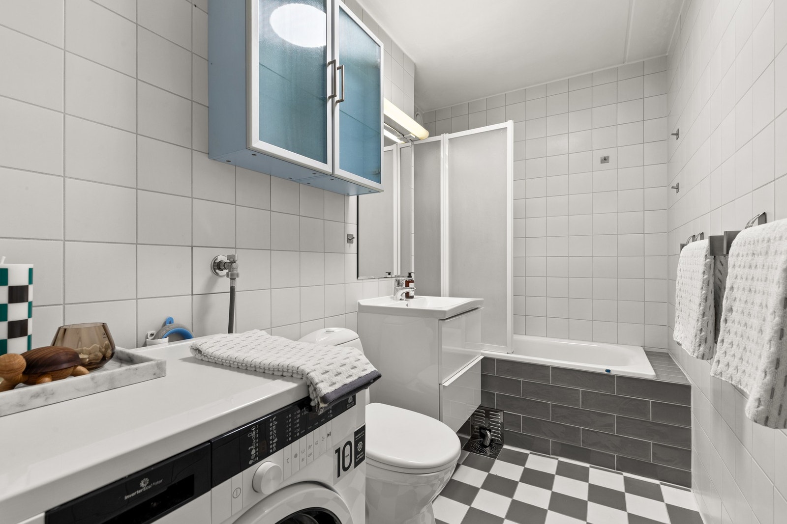 Badet er utstyrt med innfliset badekar, servantseksjon med skuffer og vask, overskap, speil med lys, gulvmontert wc og opplegg for vaskemaskin/tørketrommel. Galleribilde