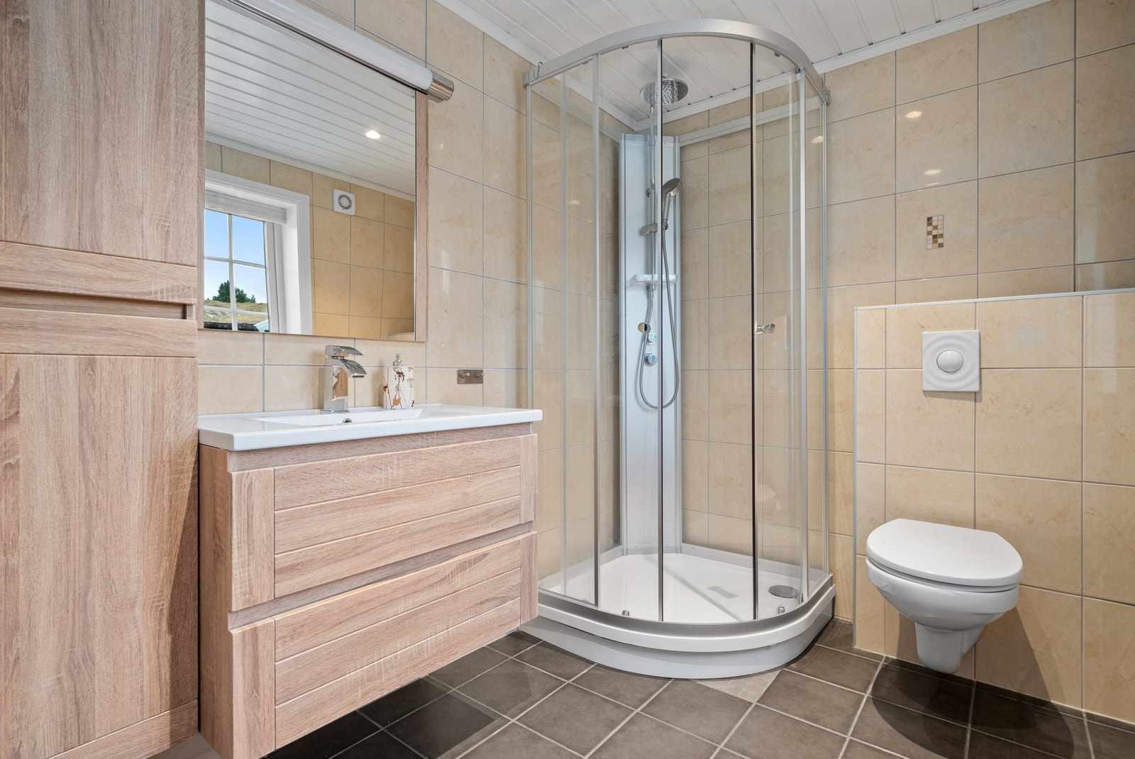 Badet er flislagt og har innredning med klosett, dusjkabinett og servant. Galleribilde