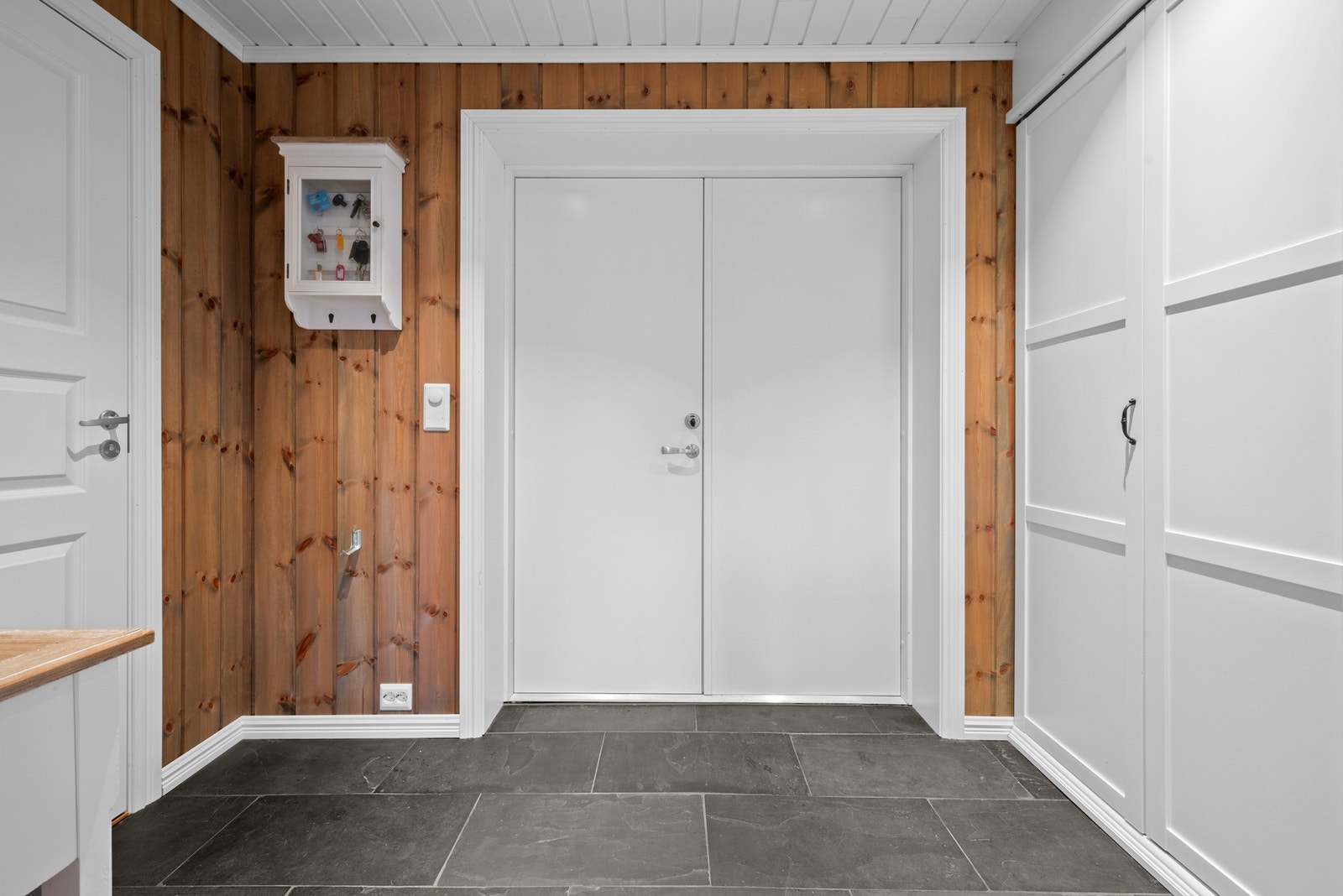 Romslig entré med fliser på gulv. God plass til klesoppheng i garderobeskap. Galleribilde