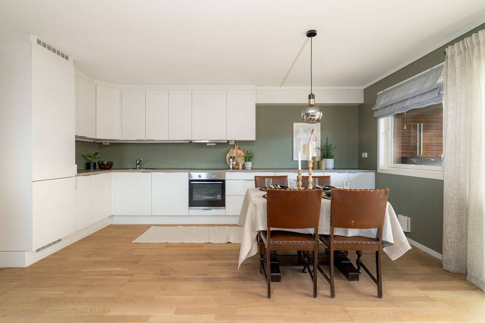 Kjøkkenet er moderne og funksjonelt, med rikelig skap- og benkeplass. Innredningen har hvite, glatte fronter, laminatbenkeplate og integrerte hvitevarer som gjør rommet både elegant og praktisk. Galleribilde