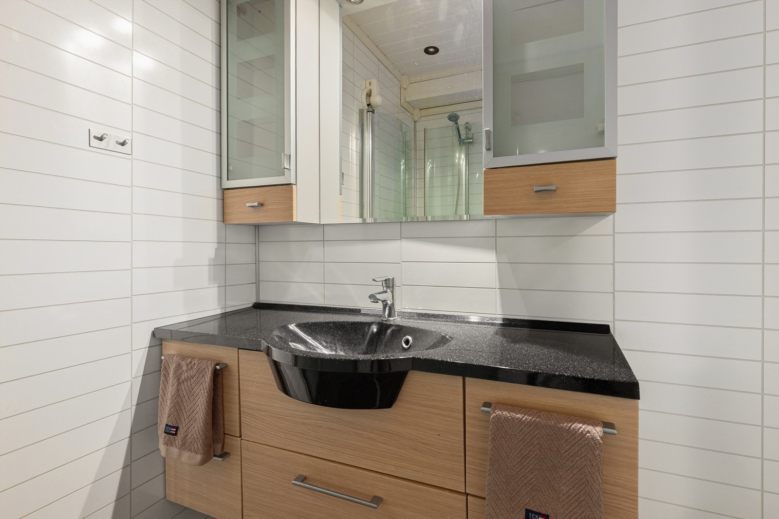 Moderne bad utstyrt med servant med innredning, dusj og toalett. Galleribilde