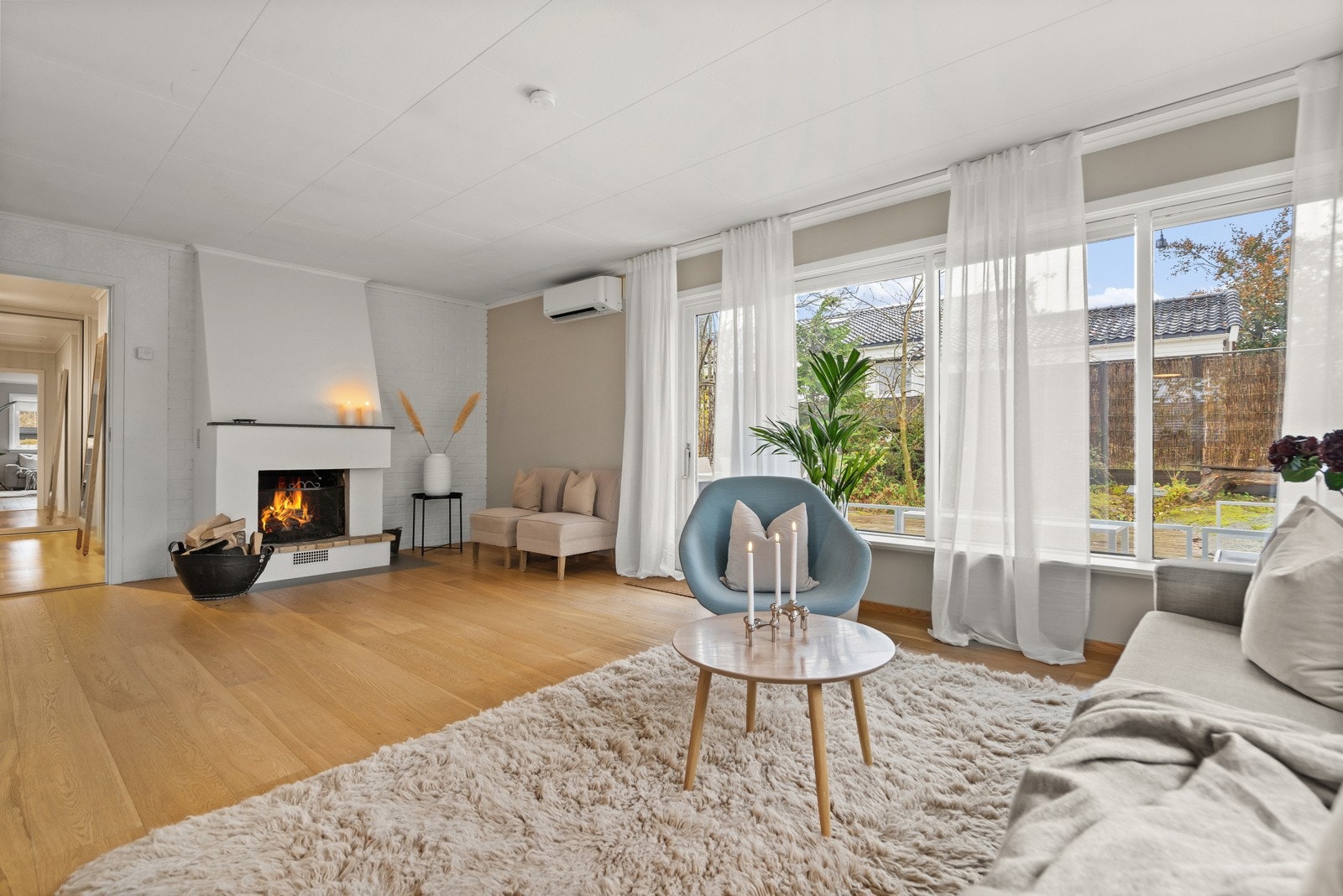 Lys og åpen stue med peis og utgang til solrik terrasse Galleribilde