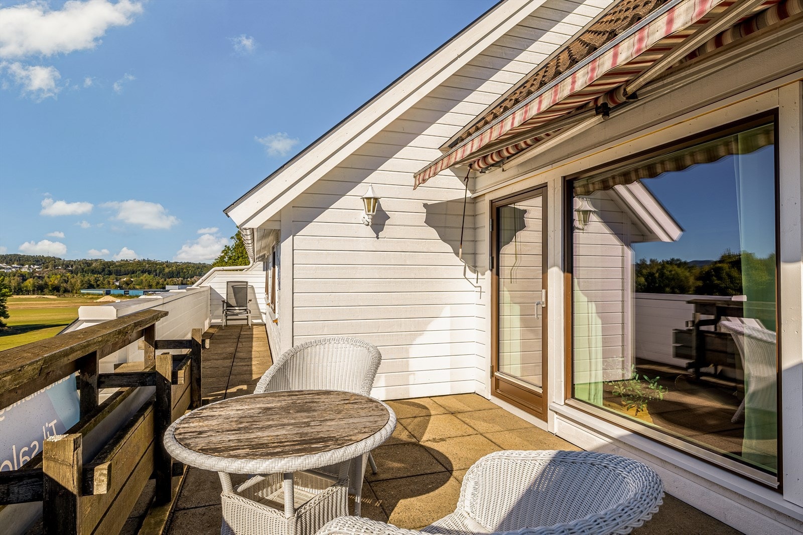 Fin uteplass med plass til flere sittegrupper og markise over balkongen Galleribilde