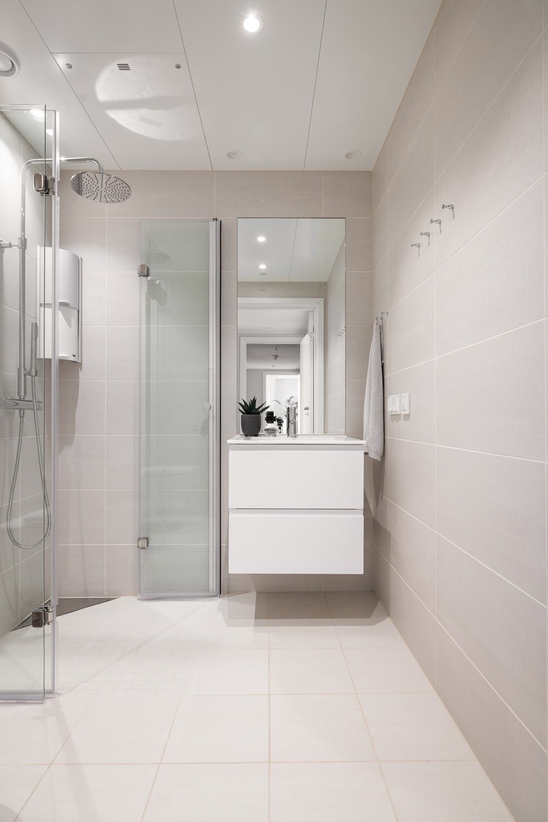 Badet har flislagte overflater, innfellbare dusjvegger med nedsenket gulv i dusjsone, downlights i himling, vask med møbel under, innebyd wc og mekanisk avtrekk. Galleribilde