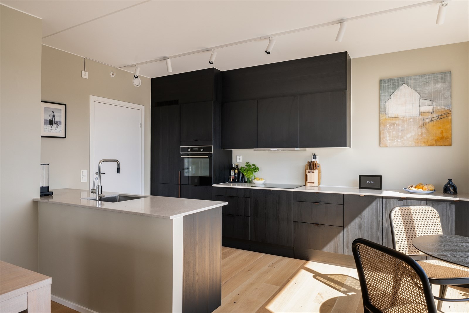 Kjøkkeninnredning består av en mørk glatt innredning fra HTH, med lys kompositt benkeplate, integrerte hvitevarer og mekanisk avtrekk. Galleribilde