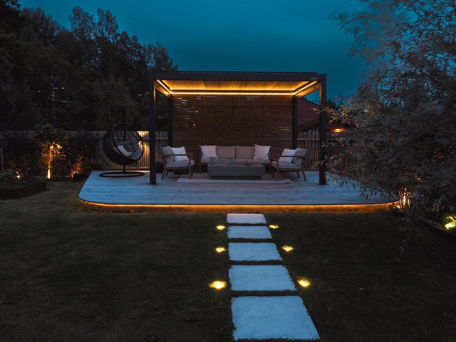 Lyssatt gangsti av heller fra uteplassen til plattingen med Pergola. Galleribilde