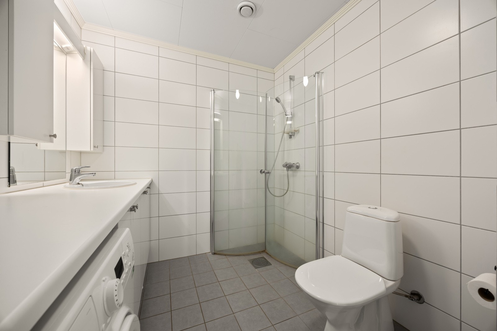 Videre er badet utstyrt med dusjhjørne med dører i herdet glass og gulvstående toalett. Galleribilde