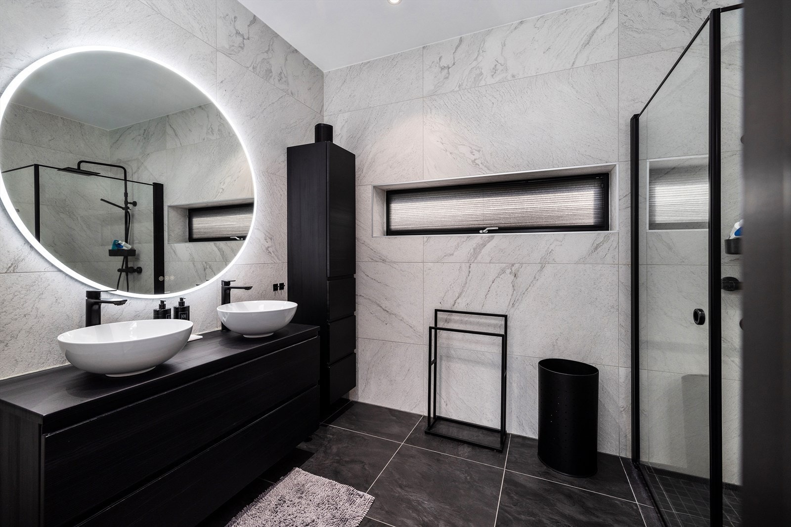 Dert andre badet er innredet med baderomsinnredning i mørk utførelse med to tidsriktige bolleservanter og rom for diverse oppbevaring i skuffeseksjon og høyskap og speil med led belysning. Galleribilde