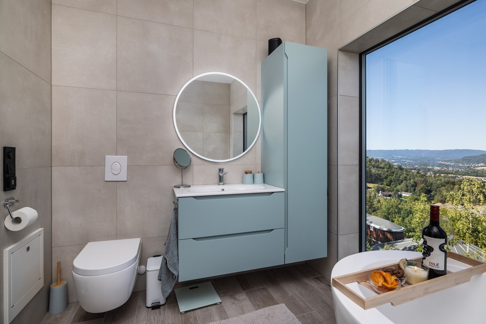 Baderomsinnredningen er dempet grønn og består av en heldekkende servant med god oppbevaringsplass skuffeseksjon og høyskap. Videre har badet rundt speil, vegghengt toalett og badekar. Galleribilde