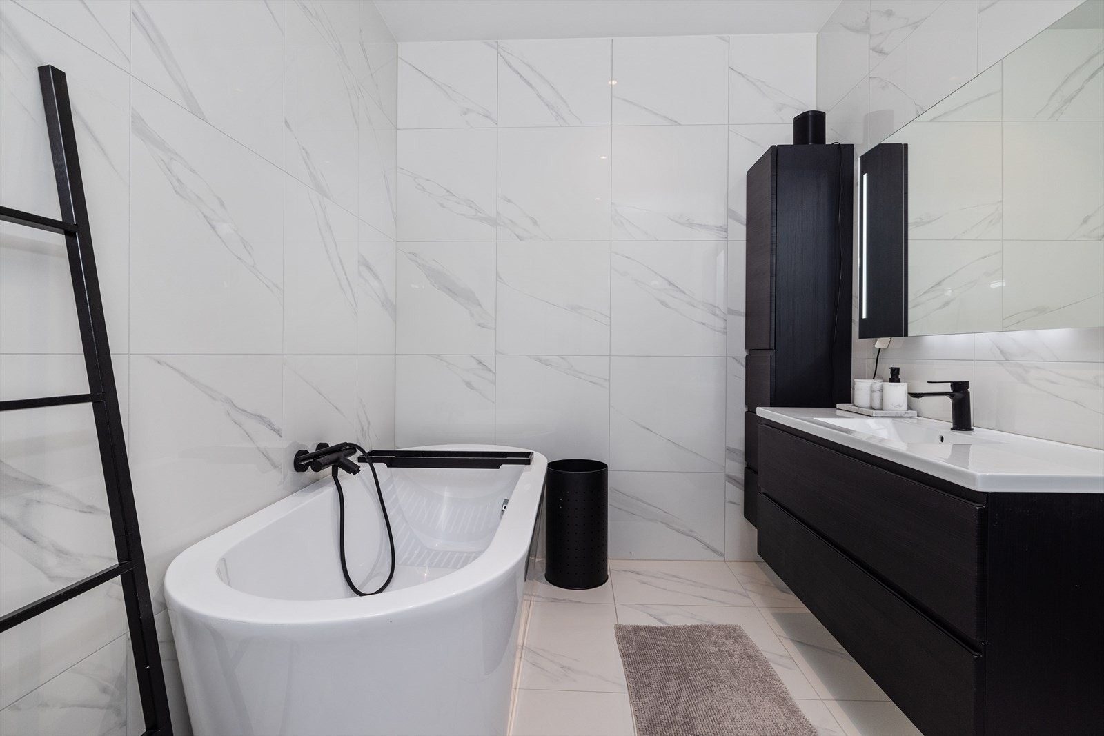 Badet er innredet med sort baderomsinnredning med heldekkende nedfelt servant med rom for oppbevaring i skuffeseksjon og høyskap, i tillegg til speil med led belysning. Galleribilde