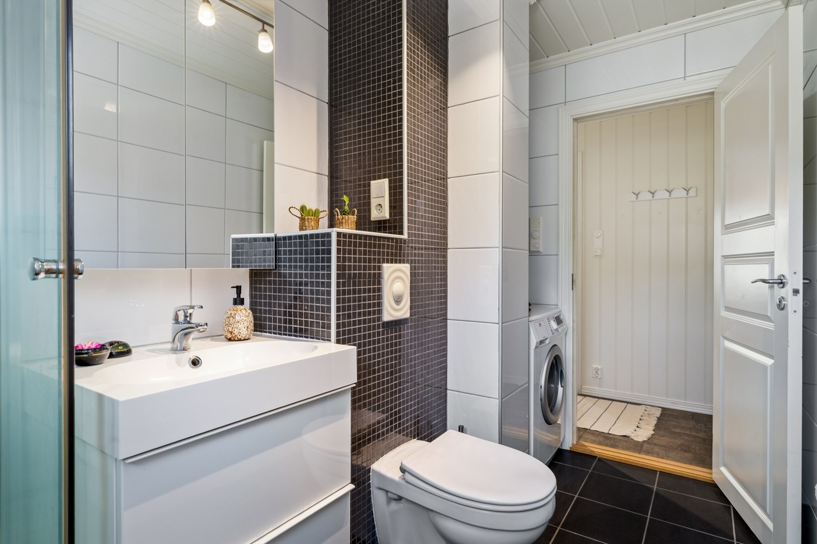 Badet har opplegg for vaskemaskin, og en smart, adskilt avdeling skaper en praktisk og funksjonell vaskesone. Denne løsningen gir en ryddig og effektiv vaskeromsavdeling. Ideelt for deg som ønsker både komfort og orden i hverdagen. Galleribilde