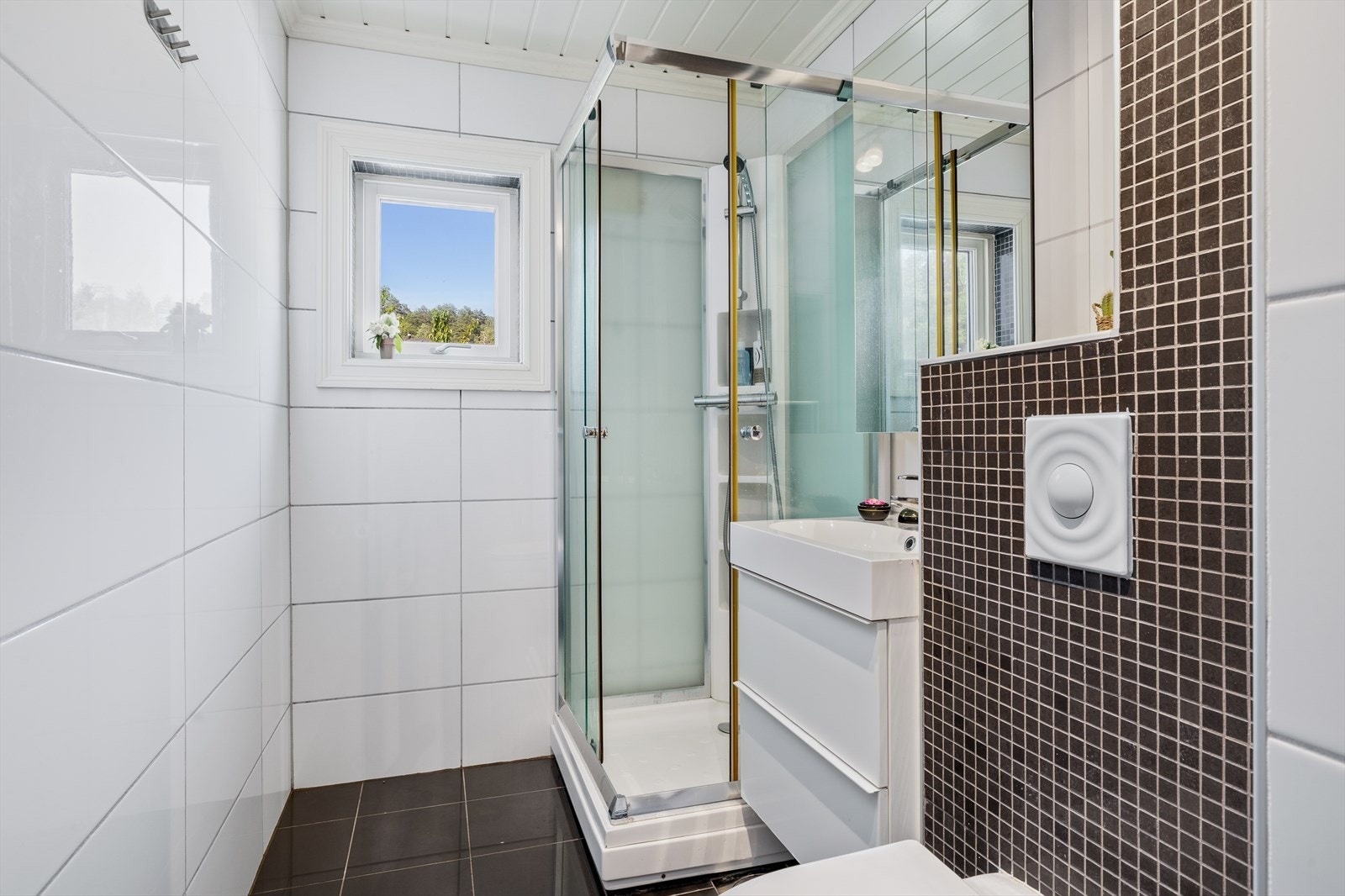 Rommet er praktisk innredet med dusjkabinett, moderne servantskap med god oppbevaringsplass, vegghengt toalett og elektrisk styrt vifte som sørger for effektiv ventilasjon. Galleribilde