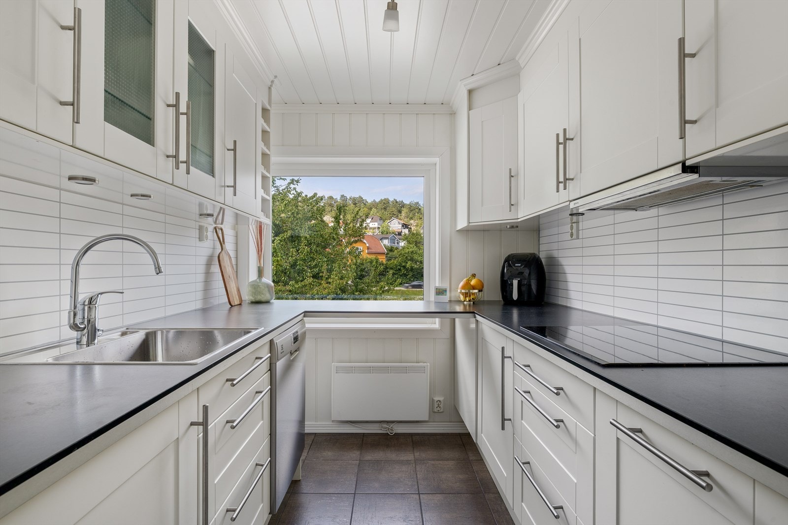 Lyst og innbydende kjøkken med klassisk innredning i hvite, profilerte fronter og praktisk laminat benkeplate. Galleribilde