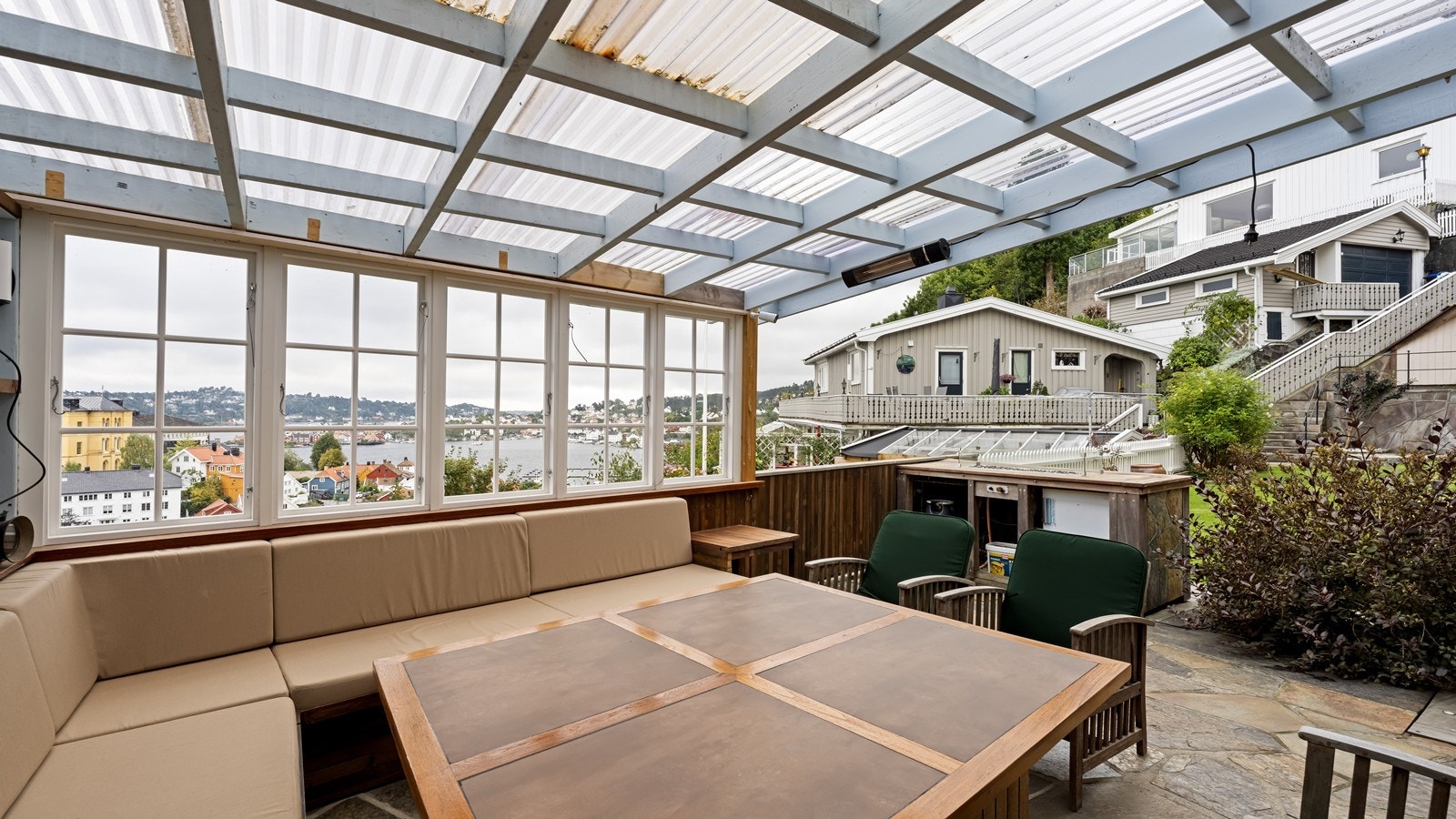 Plassbygget benk med puter og massivt bord følger boligen ved salg. Bord er kombinasjon av teak og flis og har hjul under. Galleribilde