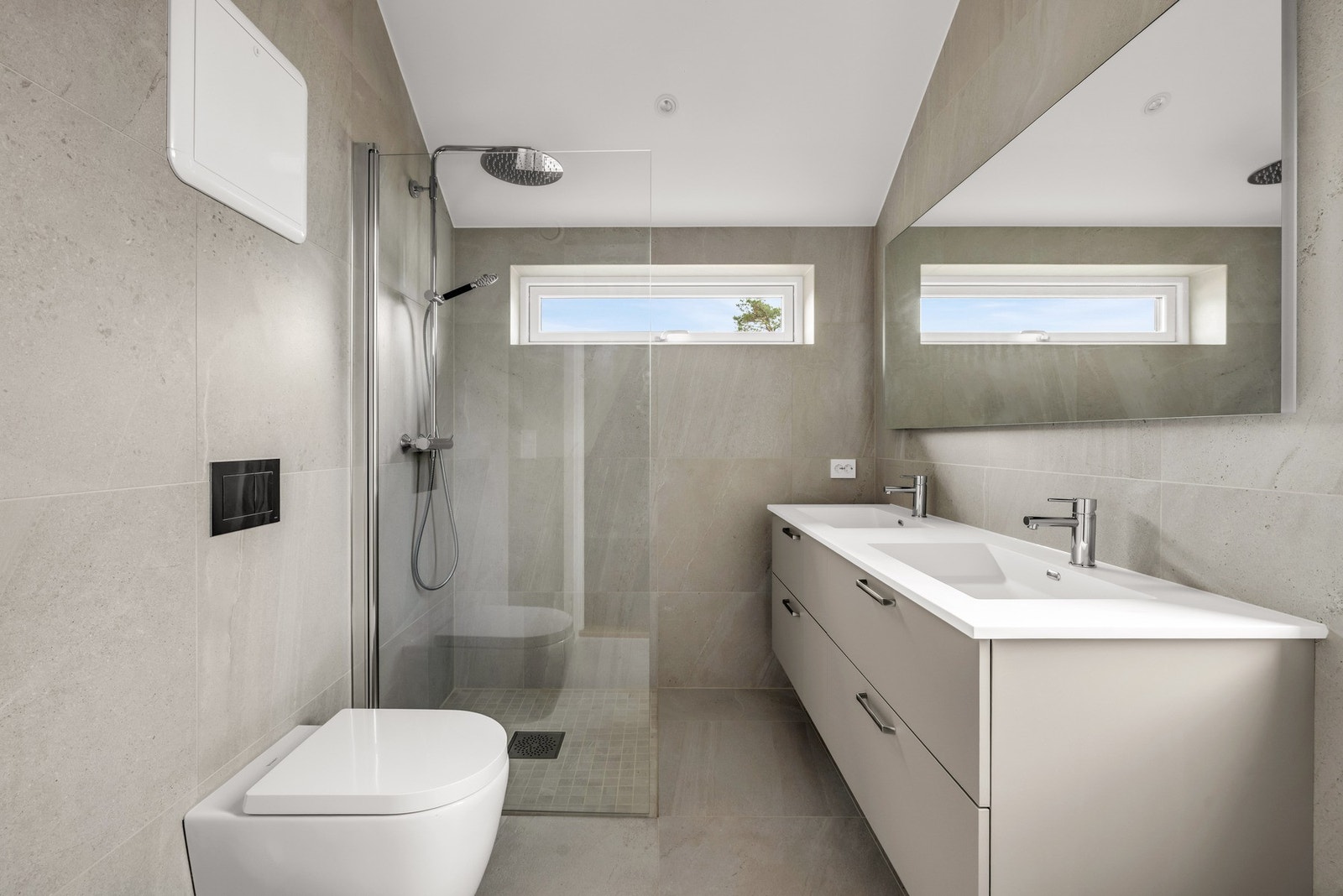 Bad/wc med dusjnisje, veggmontert toalett og dobbel servant med speil. Galleribilde