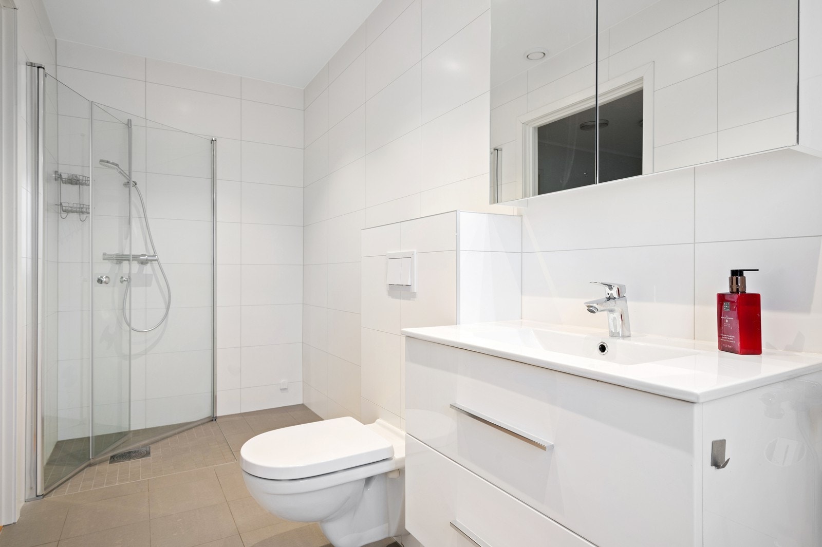 Rommet har innredning med nedfelt servant, veggmontert toalett, dusjvegger/hjørne og opplegg for vaskemaskin Galleribilde