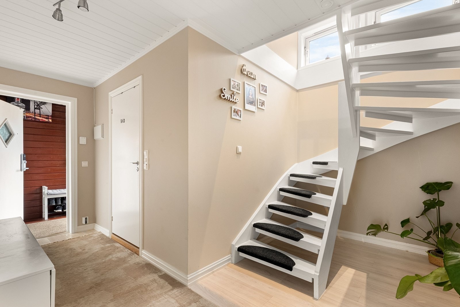 Innbydende gang i boligens første etasje bestående av bad, kjøkken og stue. Galleribilde