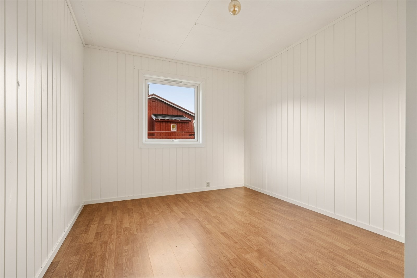 Lyst soverom med laminatgulv og panelplater på veggene. Galleribilde