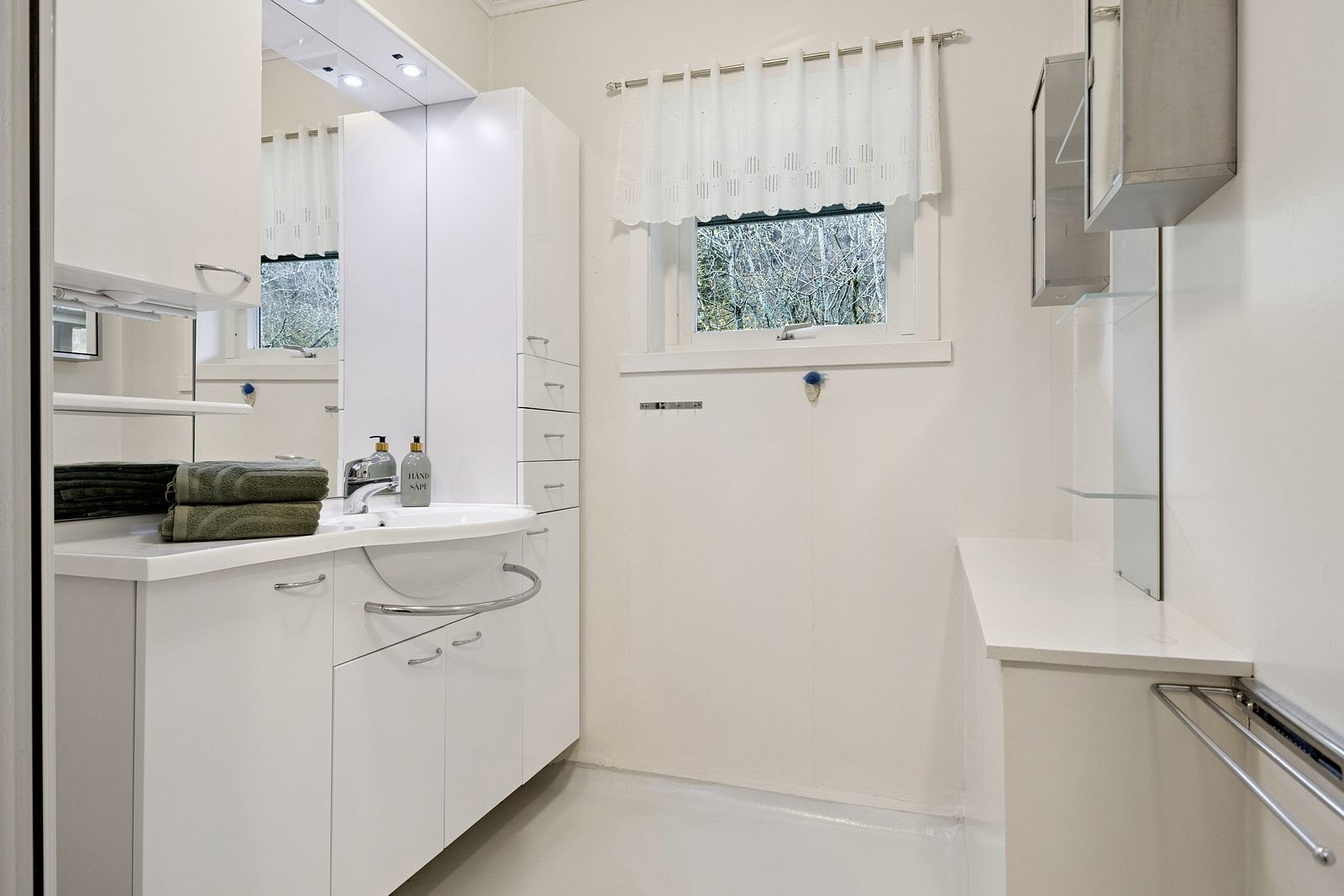 Baderommet har lys, tidløs innredning med stort speil og godt med lys Galleribilde