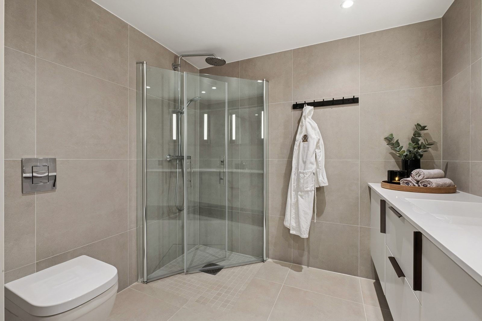 Badet er utstyrt med servantinnredning, dusjhjørne med glassdører og vegghengt toalett. Galleribilde