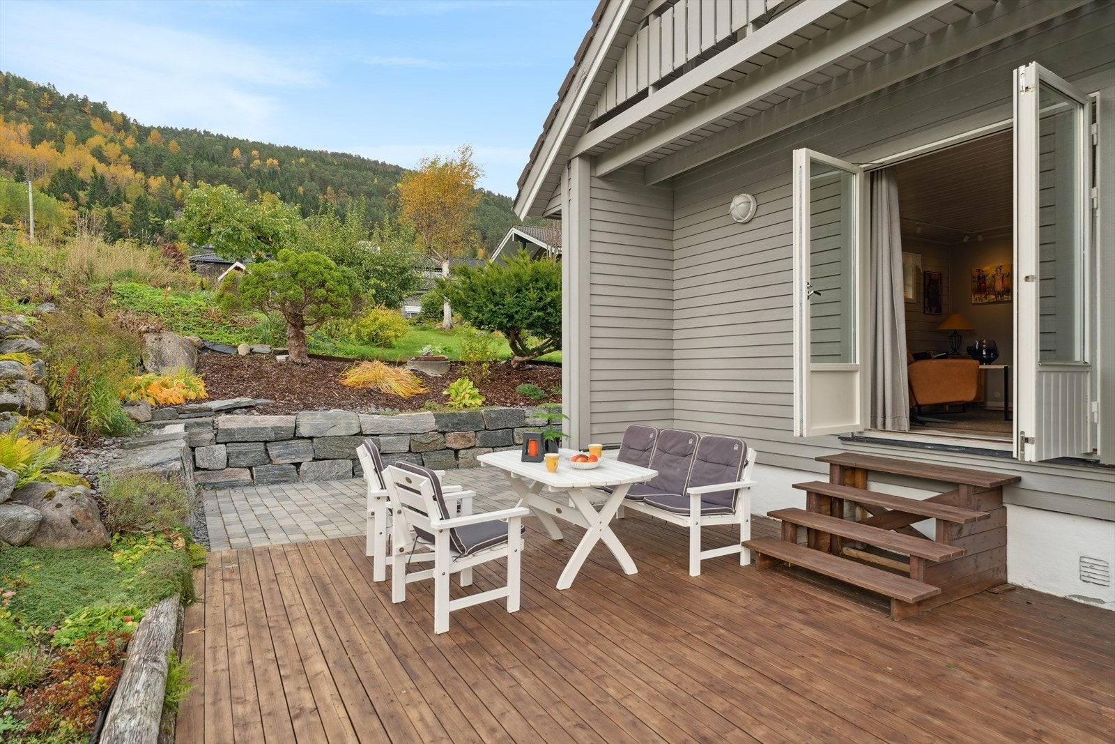 Pent opparbeidet uteområde med terrasseplatting, belegningsstein og hageareal. Galleribilde