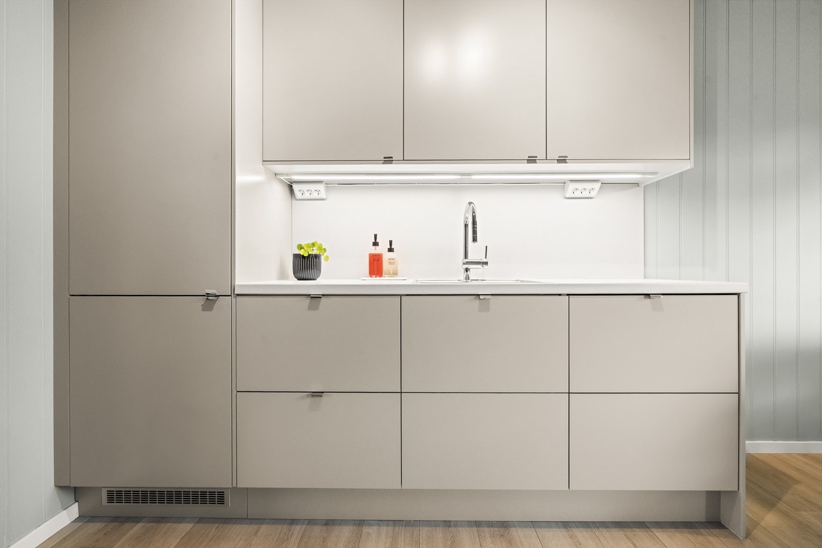 Kjøkkenet har laminert benkeplate med underlimt vask, plater på veggane og led-lys over benken på denne sida. Galleribilde